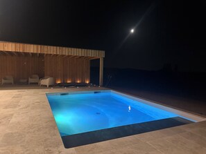 Ein Pool mit Holzterrasse und Liegestühlen.