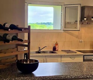 Uma cozinha com janela, espaço para vinhos e pia.