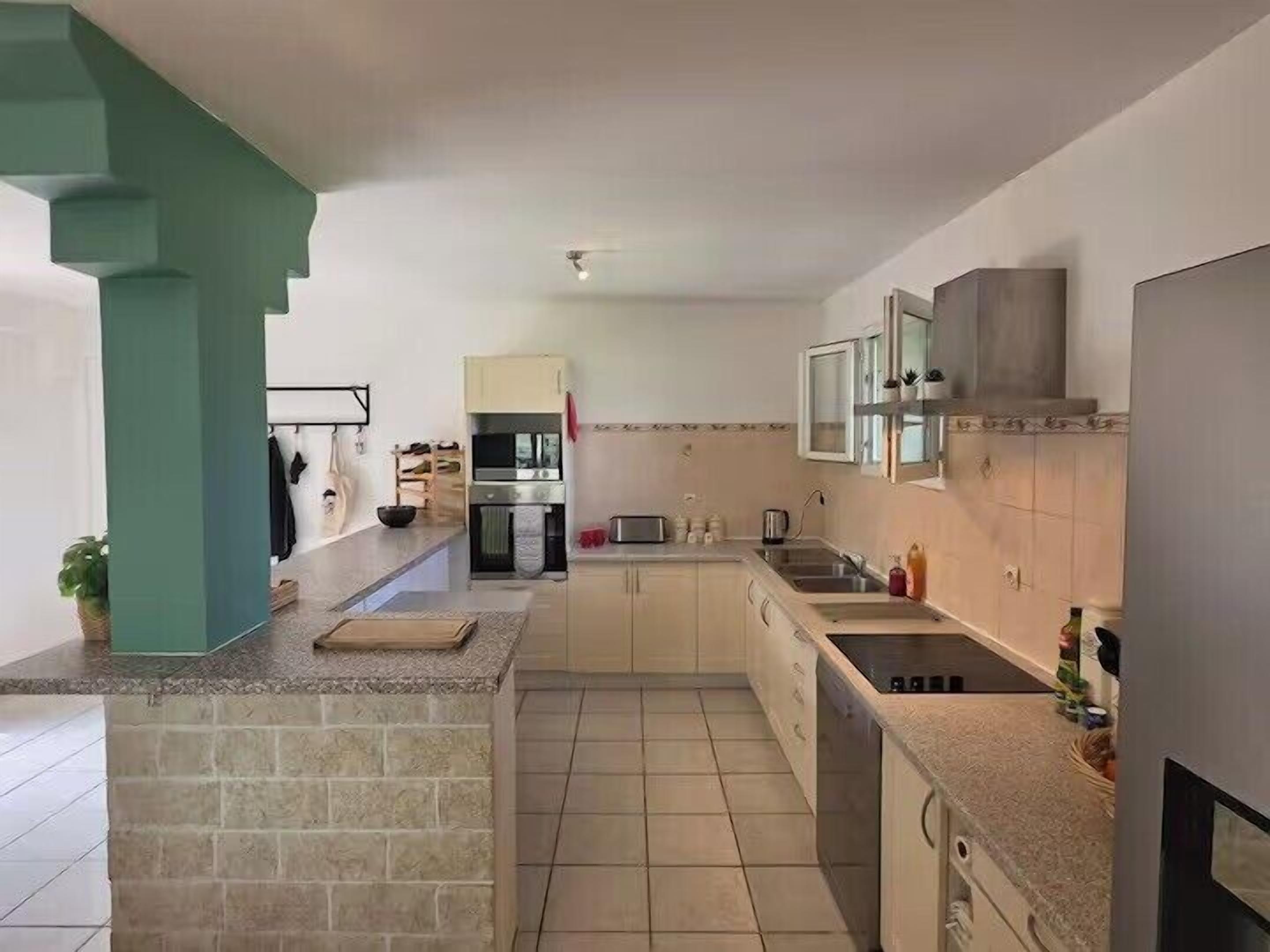 A kitchen with a central island, built-in appliances, and a tiled backsplash.