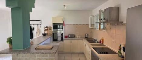 A kitchen with a central island, built-in appliances, and a tiled backsplash.