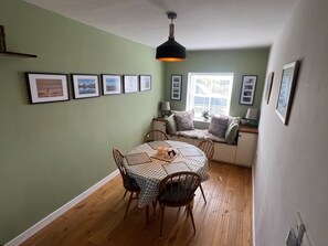 Ein Essbereich mit einem runden Tisch, Stühlen, einer karierten Tischdecke und gerahmten Bildern an der Wand.