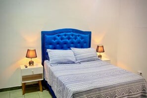 A bed with a tufted headboard, two bedside lamps, and a patterned bedspread.