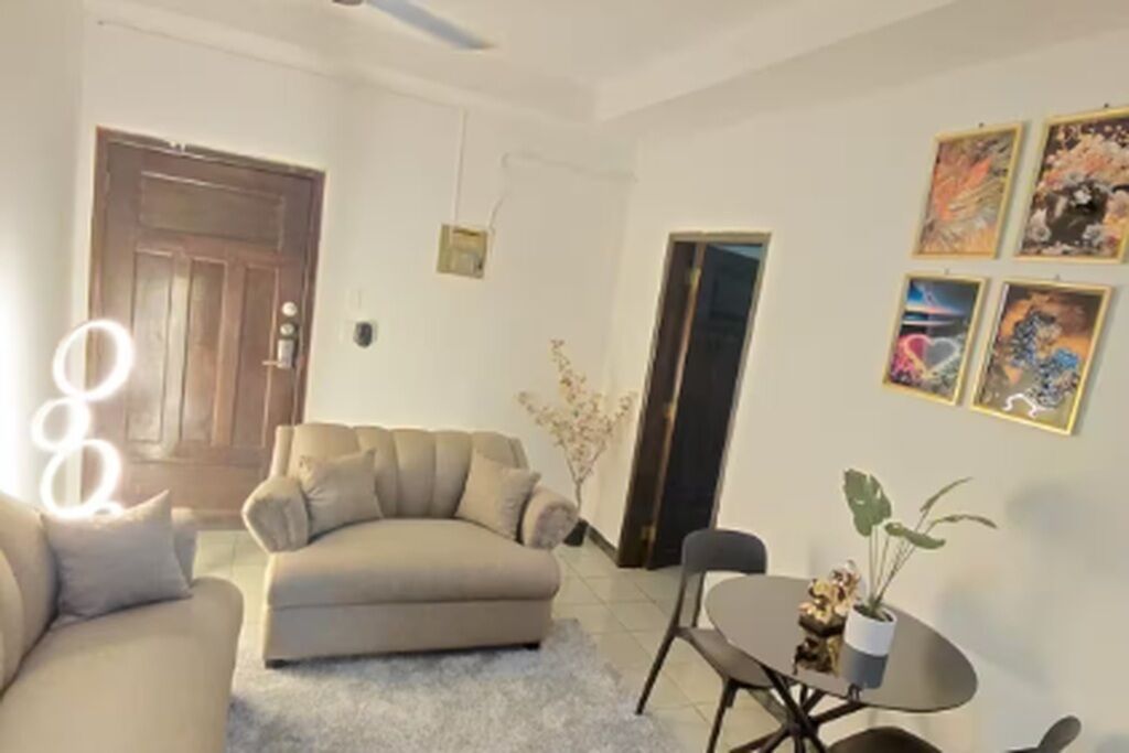 A living room with a sofa, a small table with chairs, and a door.