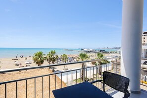 Ein Balkon mit Blick auf einen Strand, Palmen und eine Stadt am Horizont.