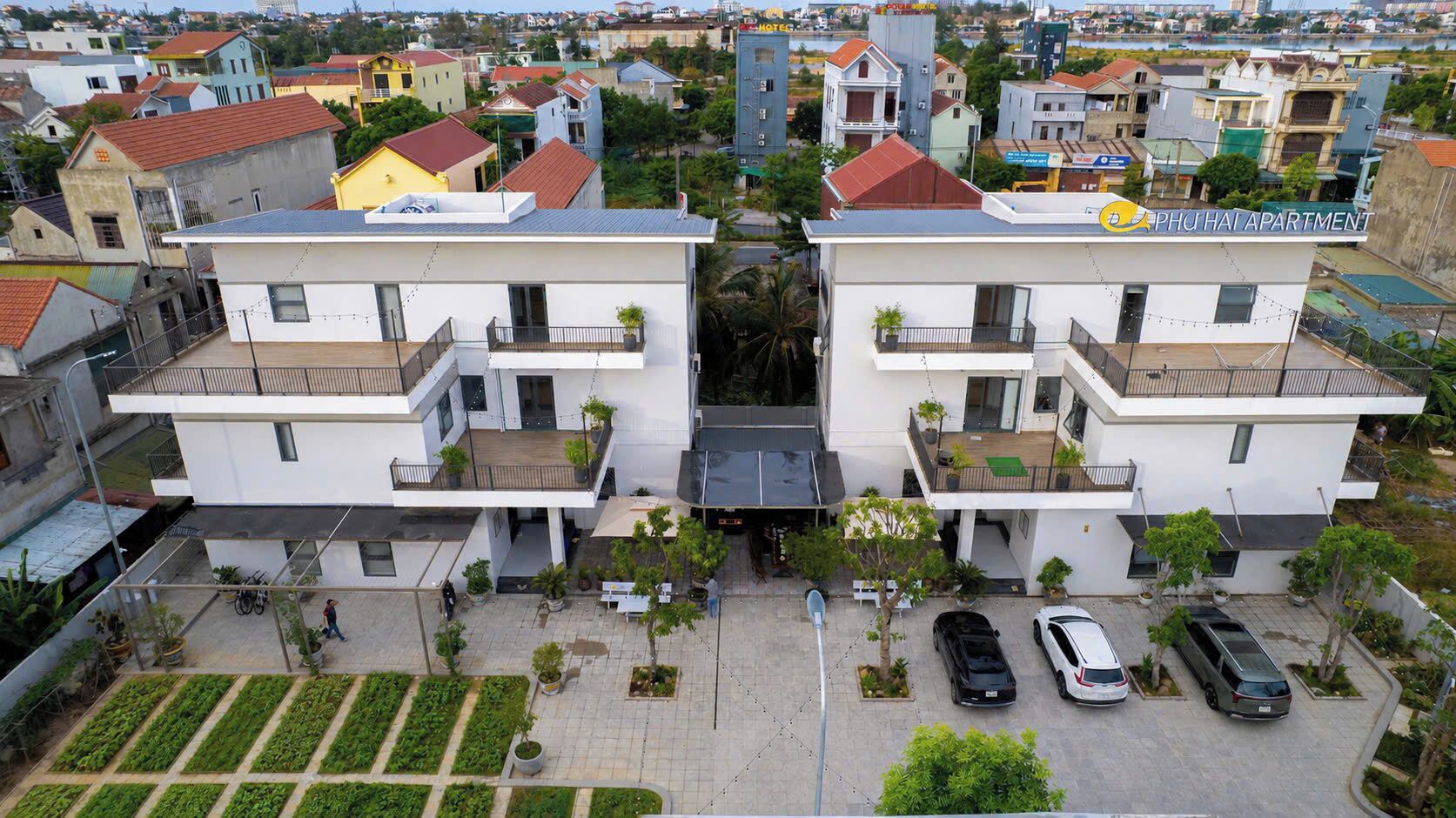 Ein modernes Mehrfamilienhaus mit Dachterrasse, Parkplatz und gepflegtem Garten.