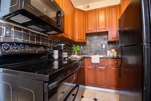 Una cucina con piano cottura nero, mobili in legno e frigorifero nero.