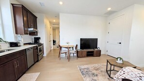 A compact living space with a kitchenette, a dining area, a TV, and a door. - Modern 1BR/1BA with Attached Garage private entrance and Patio (Lone Tree)