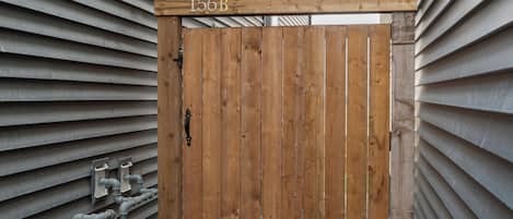 A wooden gate with a sign reading '156B' and a metal lock.