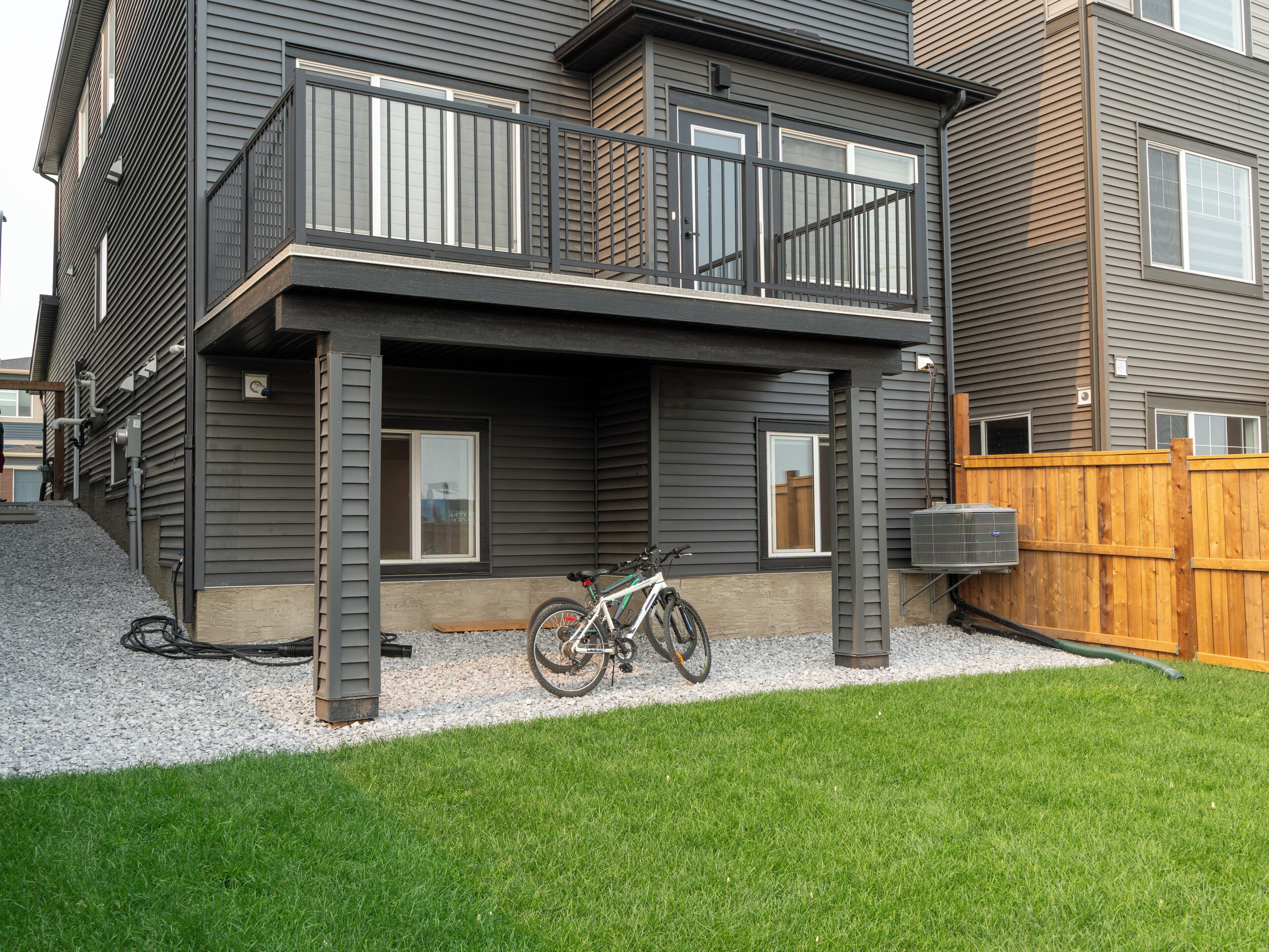 A two-story residential building with a balcony, a bicycle parked outside, and a wooden fence.