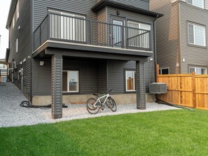 En toetages boligbygning med balkon, en cykel parkeret udenfor og et træhegn.