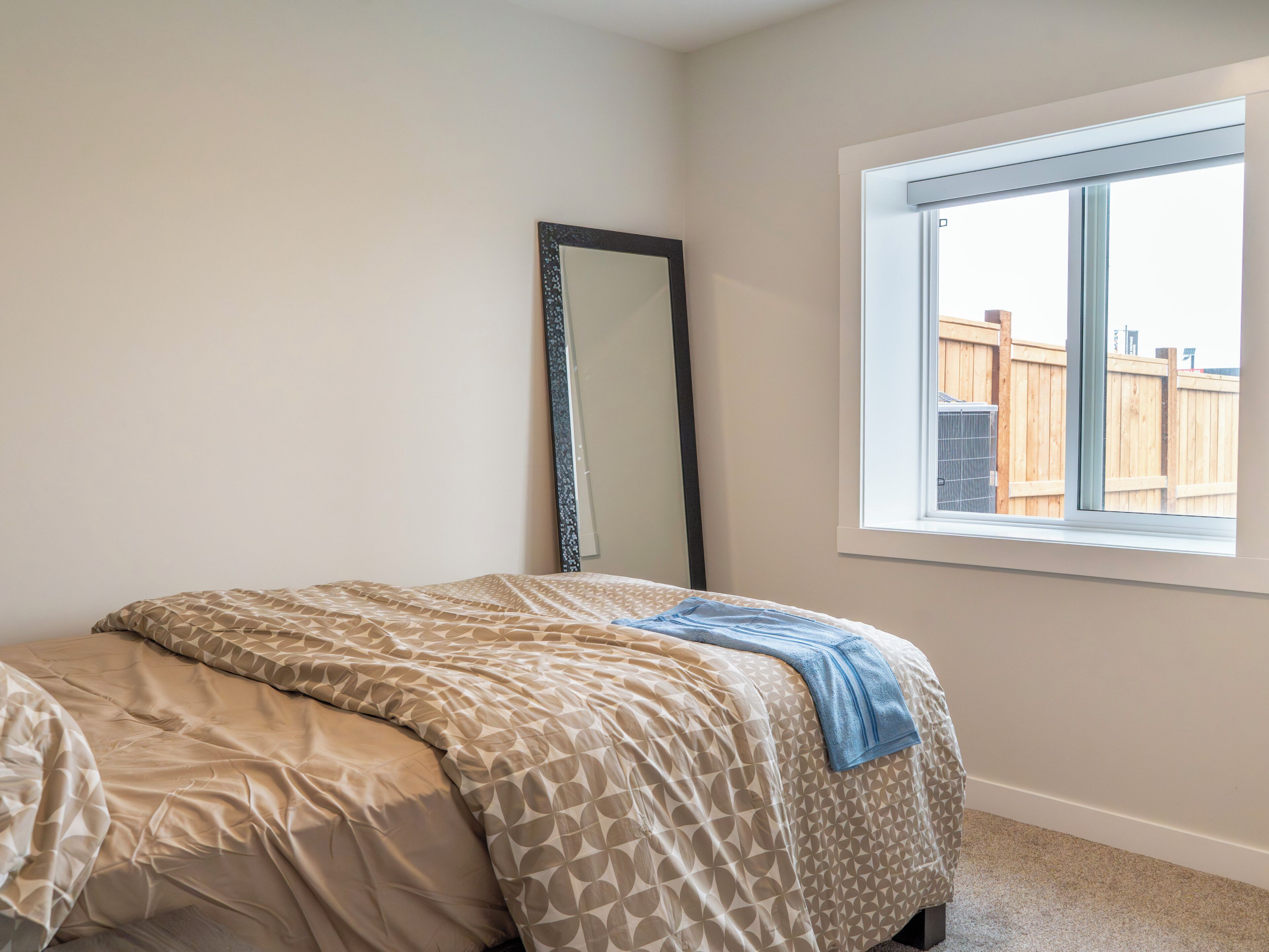 A bedroom with a bed, a window, and a mirror.