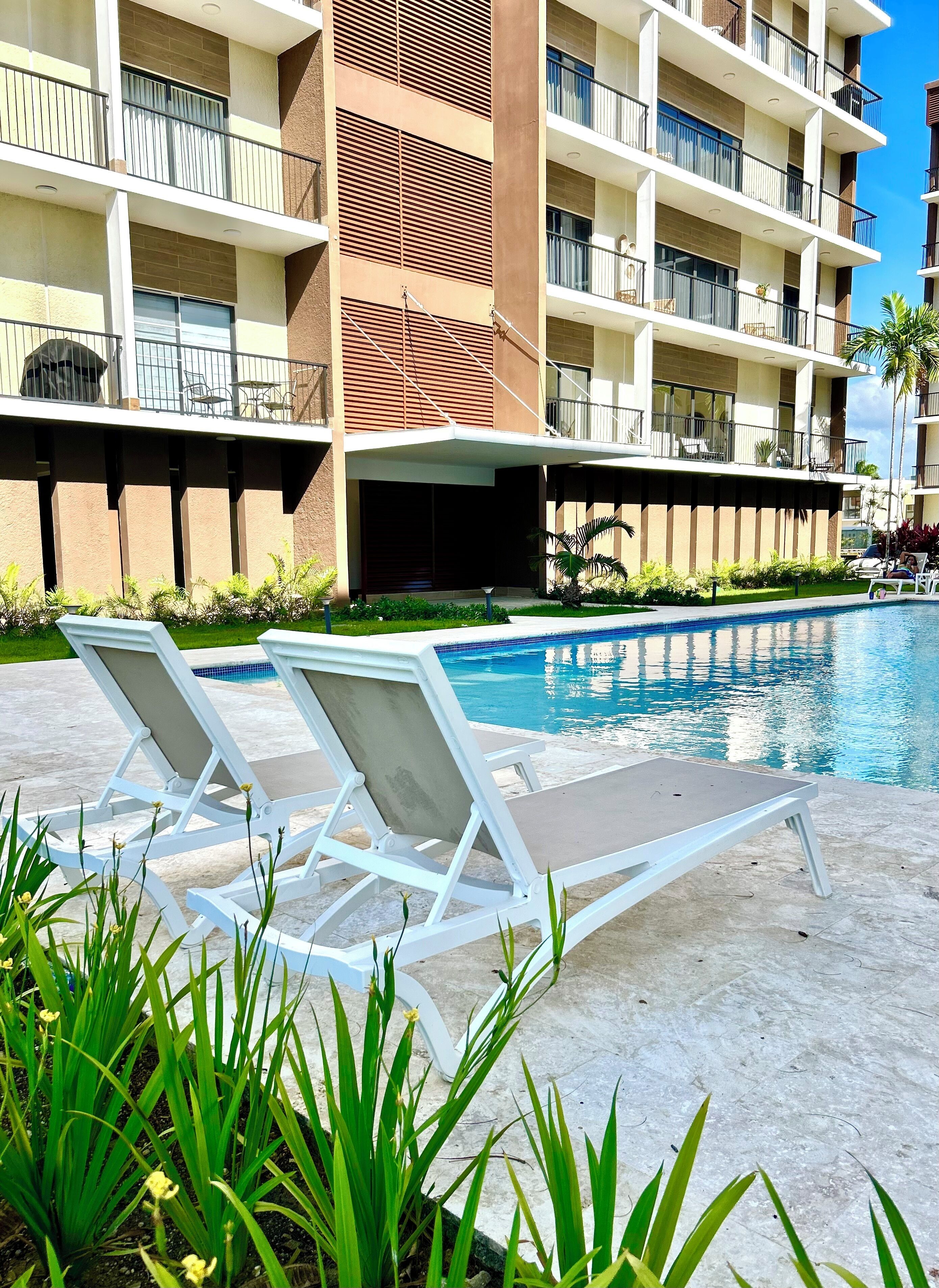 Un hôtel doté d’une piscine, de chaises longues et d’un jardin bien entretenu.
