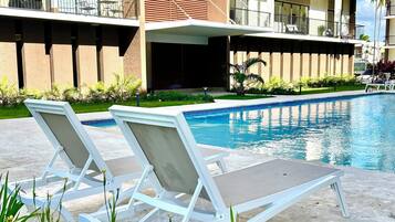 Un hôtel doté d’une piscine, de chaises longues et d’un jardin bien entretenu.