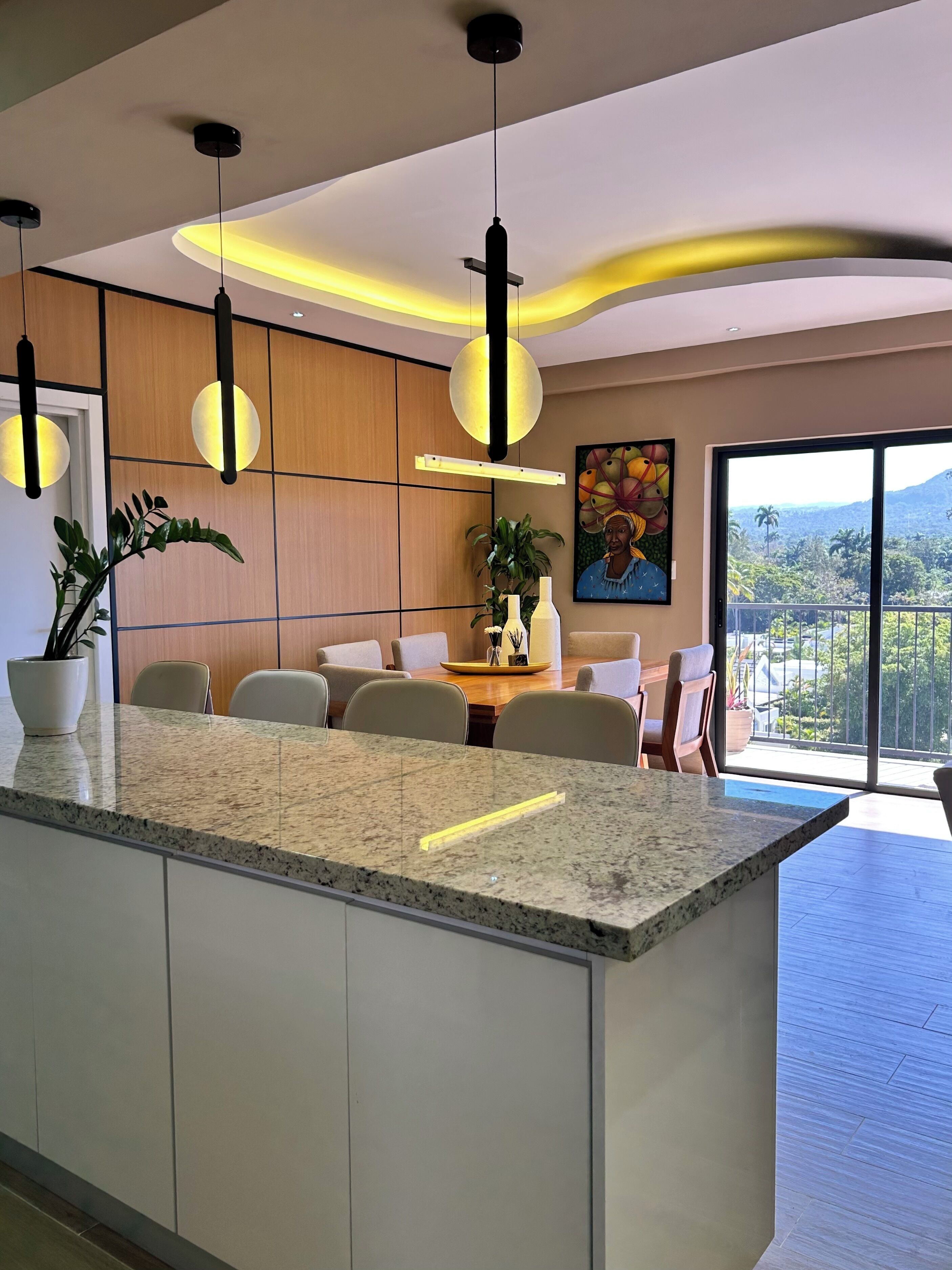 Une cuisine moderne dotée d’un îlot central, de luminaires suspendus et d’un coin repas avec des chaises et une table.