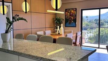 Une cuisine moderne dotée d’un îlot central, de luminaires suspendus et d’un coin repas avec des chaises et une table.