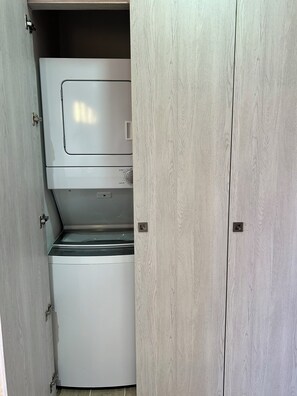 A compact, built-in washer and dryer unit with a minimalist design, integrated into a light-colored wooden cabinet. - Charming 2-bedroom apartment with AC in perfect Puerto Plata (Puerto Plata)