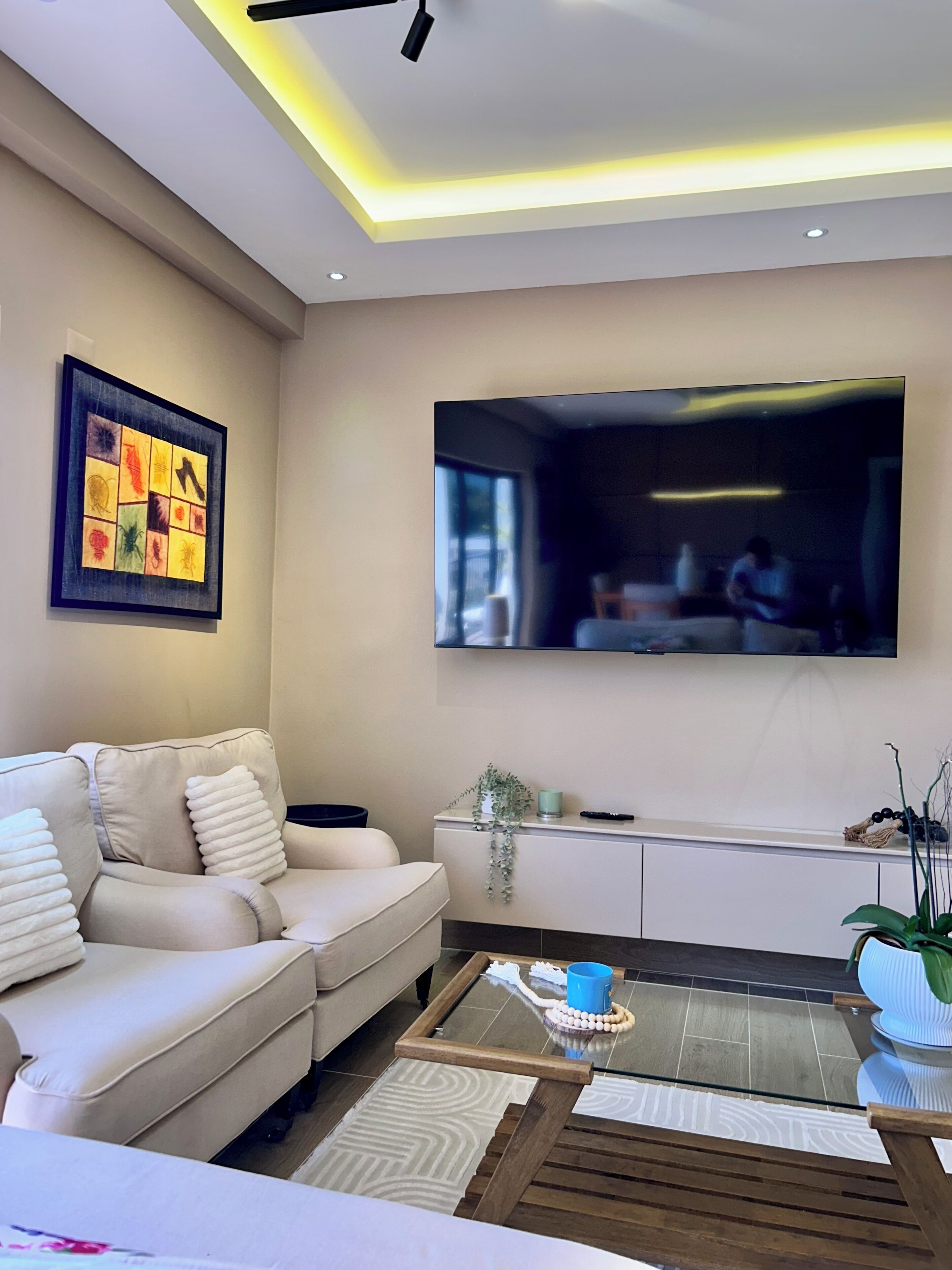 Un salon moderne avec un canapé, une table basse et un téléviseur à écran plat fixé au mur.