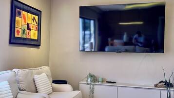 Un salon moderne avec un canapé, une table basse et un téléviseur à écran plat fixé au mur.