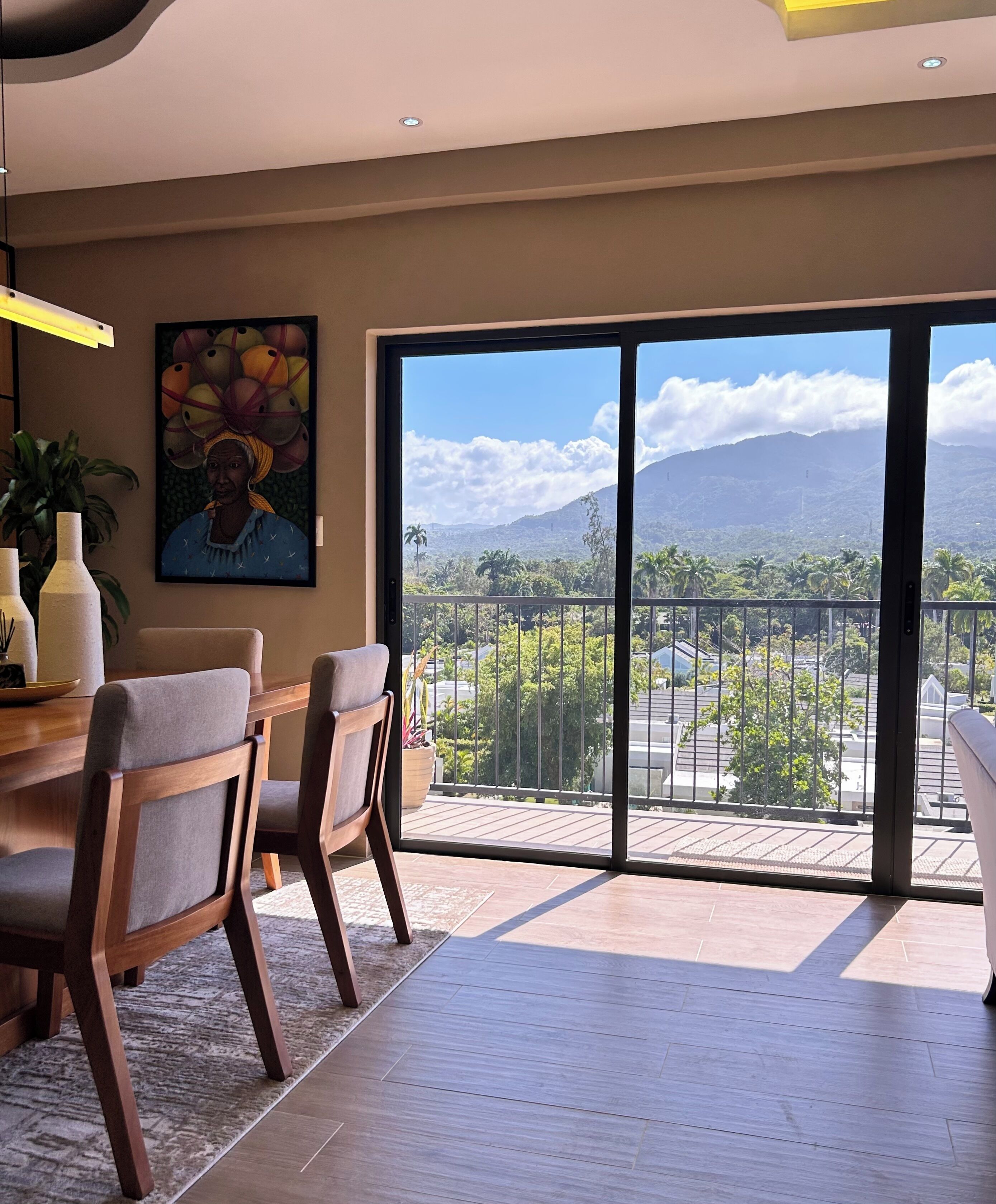 Ein modernes Wohnzimmer mit Essbereich, große Schiebeglasfenster mit Blick auf Berge und einen Balkon.