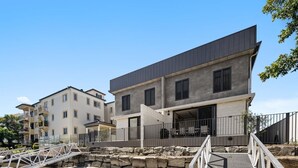 Un bâtiment moderne doté d’un toit plat, d’un espace extérieur couvert et d’un mur de soutènement en pierre.
