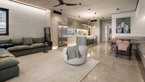Un salon moderne comprenant un canapé, un pouf et un coin repas avec des chaises et une table.