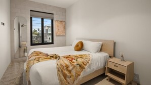 Une chambre à coucher avec un lit, une table de chevet, une fenêtre et un ventilateur de plafond.