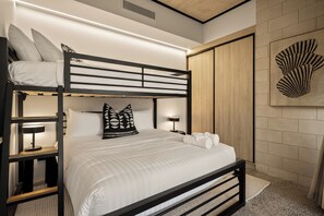 A bunk bed with a headboard, a bedside table with a lamp, and a wall-mounted artwork. - Stone & Tide by Aryve (Runaway Bay)