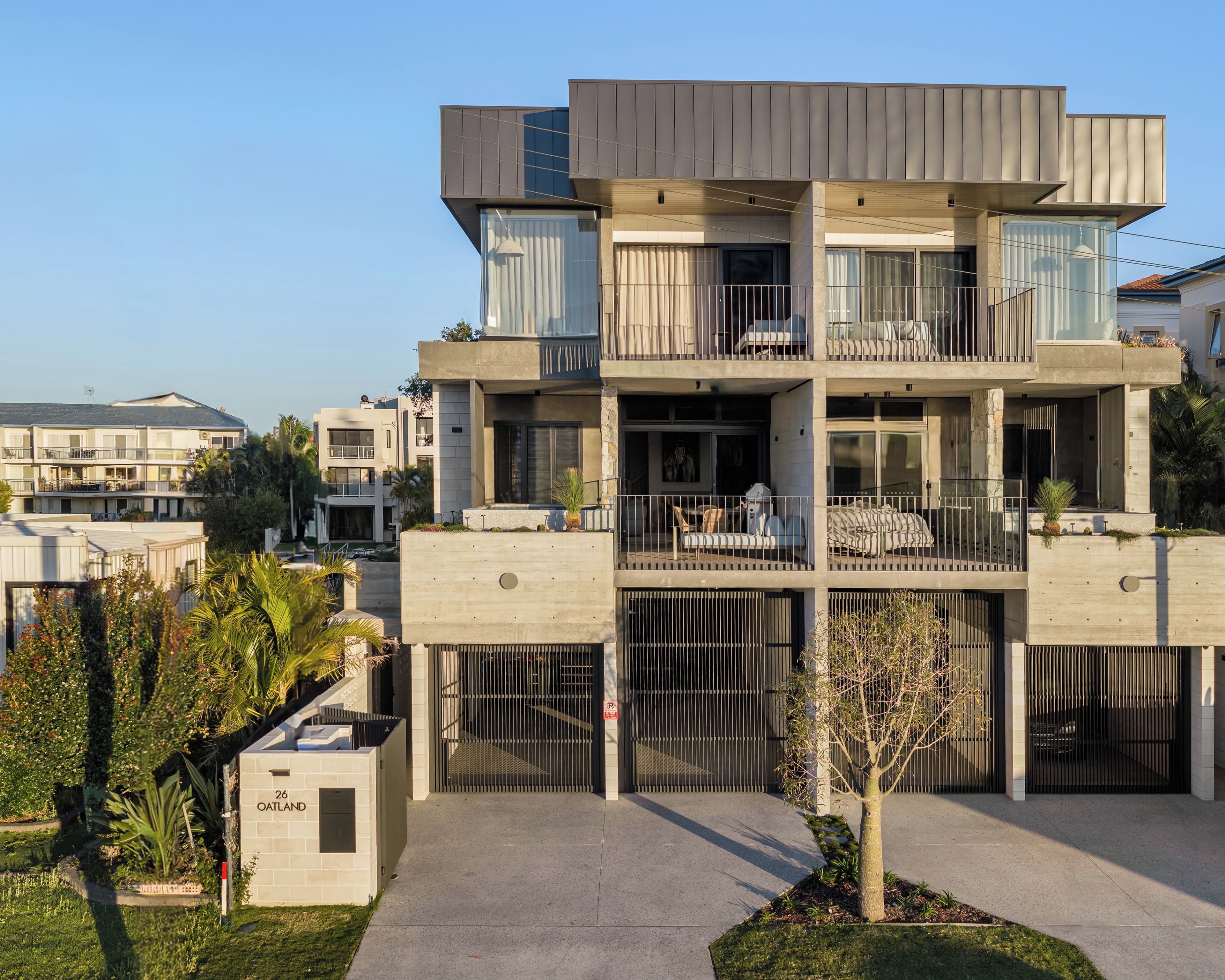 Un immeuble résidentiel moderne à plusieurs étages, doté de balcons, d’une entrée sécurisée et d’une pelouse bien entretenue.