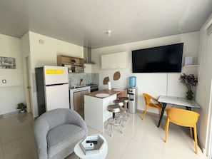 A modern kitchen with a refrigerator, microwave, and stove. There is a dining area with a table and chairs, a TV mounted on the wall, and a water dispenser. - Entire Place: Accommodation in San Miguel, El Salvador (San Miguel)