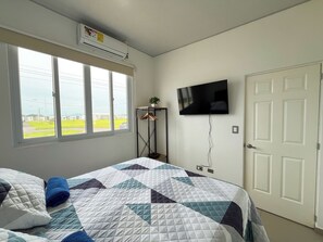 A bedroom with a bed, a TV mounted on the wall, a window with a view of the outdoors, and an air conditioning unit above the window. - Entire Place: Accommodation in San Miguel, El Salvador (San Miguel)