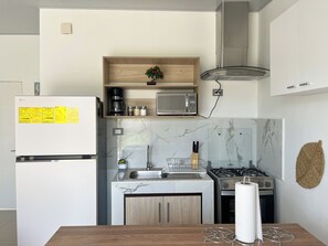 A modern kitchen with a built-in microwave, stove, and sink. There is a wooden shelf above the microwave and a small plant on it. - Entire Place: Accommodation in San Miguel, El Salvador (San Miguel)