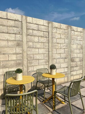 An outdoor seating area with metal chairs and tables, a concrete wall, and potted plants. - Entire Place: Accommodation in San Miguel, El Salvador (San Miguel)