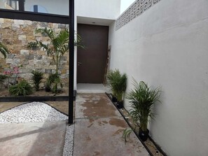 A courtyard with a stone wall, potted plants, and a concrete pathway. - 3-bedroom house (Mérida)