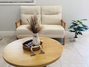 A round wooden coffee table with a woven basket and a vase of dried plants. - Cozy 1-bedroom apartment in beautiful Tampa with AC (Tampa)
