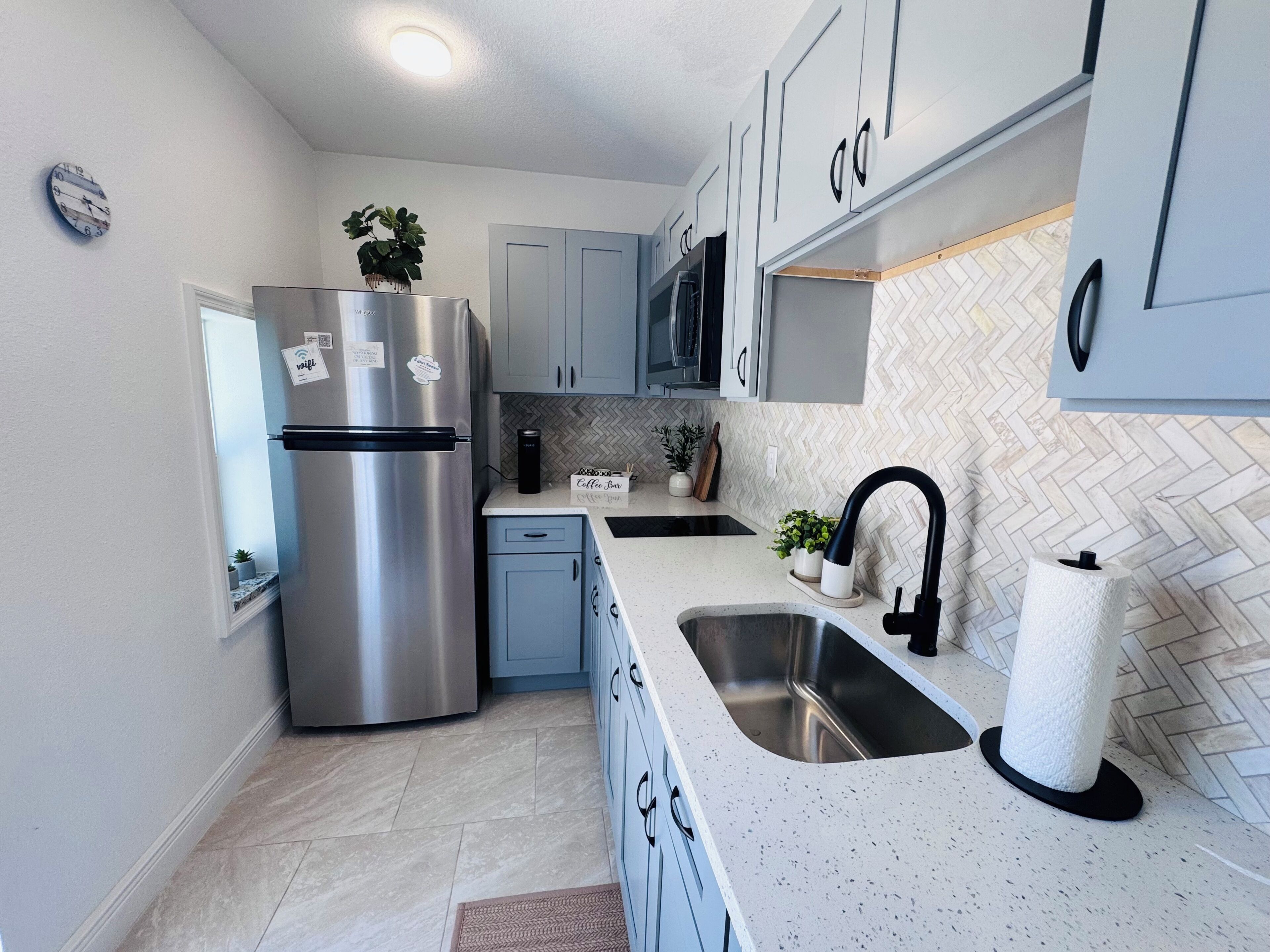 Uma cozinha moderna com eletrodomésticos de aço inoxidável, backsplash em padrão herringbone e pia dupla.