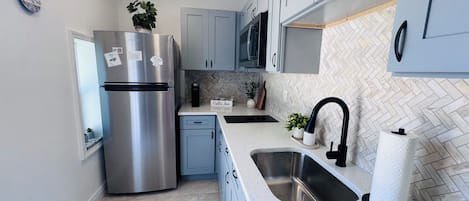 Uma cozinha moderna com eletrodomésticos de aço inoxidável, backsplash em padrão herringbone e pia dupla.