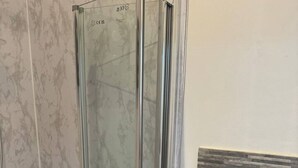 A bathroom with a glass shower enclosure, a white sink, and a tiled wall. - Spacious 4BR 4bath With Free Parking in Manchester (Manchester)