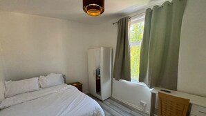 A bedroom with a bed, a wardrobe, a desk, and a window with curtains. - Spacious 4BR 4bath With Free Parking in Manchester (Manchester)