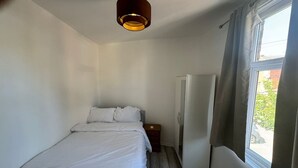 A bedroom with a bed, a nightstand, a wardrobe, and a window with curtains. - Spacious 4BR 4bath With Free Parking in Manchester (Manchester)