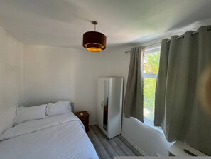 A bedroom with a bed, a wardrobe, a nightstand, and a window with curtains. - Spacious 4BR 4bath With Free Parking in Manchester (Manchester)