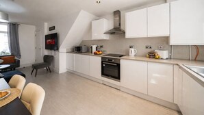 Eine moderne Küche mit weißen Schränken, einem Backofen und einer Mikrowelle.