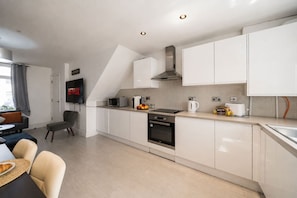 A modern kitchen with white cabinets, a built-in oven, and a microwave. - Premium 3 Bed Cardiff City Sleeps 9 With Free Parking (Cardiff)