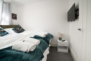 A hotel room with a bed, a bedside table with a lamp, and a TV mounted on the wall. - Premium 3 Bed Cardiff City Sleeps 9 With Free Parking (Cardiff)