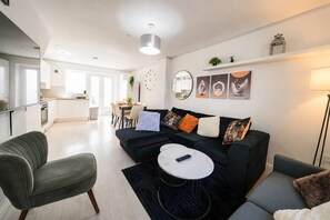 A modern living room with a black sofa, a round coffee table, and a grey armchair. - Premium 3 Bed Cardiff City Sleeps 9 With Free Parking (Cardiff)