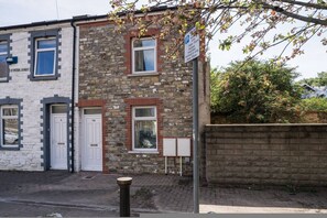 A two-story building with a stone facade, white doors, and a parking sign indicating limited parking hours. - Premium 3 Bed Cardiff City Sleeps 9 With Free Parking (Cardiff)
