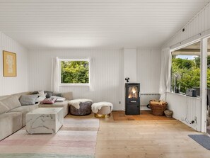 A cozy room with a sofa, ottoman, and a wood-burning stove. - "Ulli" - 350m from the sea by Interhome (Grenaa)