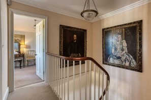 A hallway with a staircase, a door leading to a room, and two framed portraits on the wall. - The Orangery -  Bridgnorth , Shropshire (Bridgnorth)