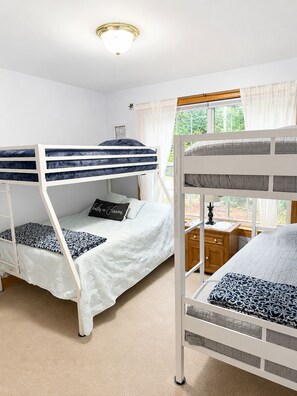A room with bunk beds, a window with curtains, a bedside table, and a lamp. - 3 bedroom, 2 bath house with endless activities (Bridgton)