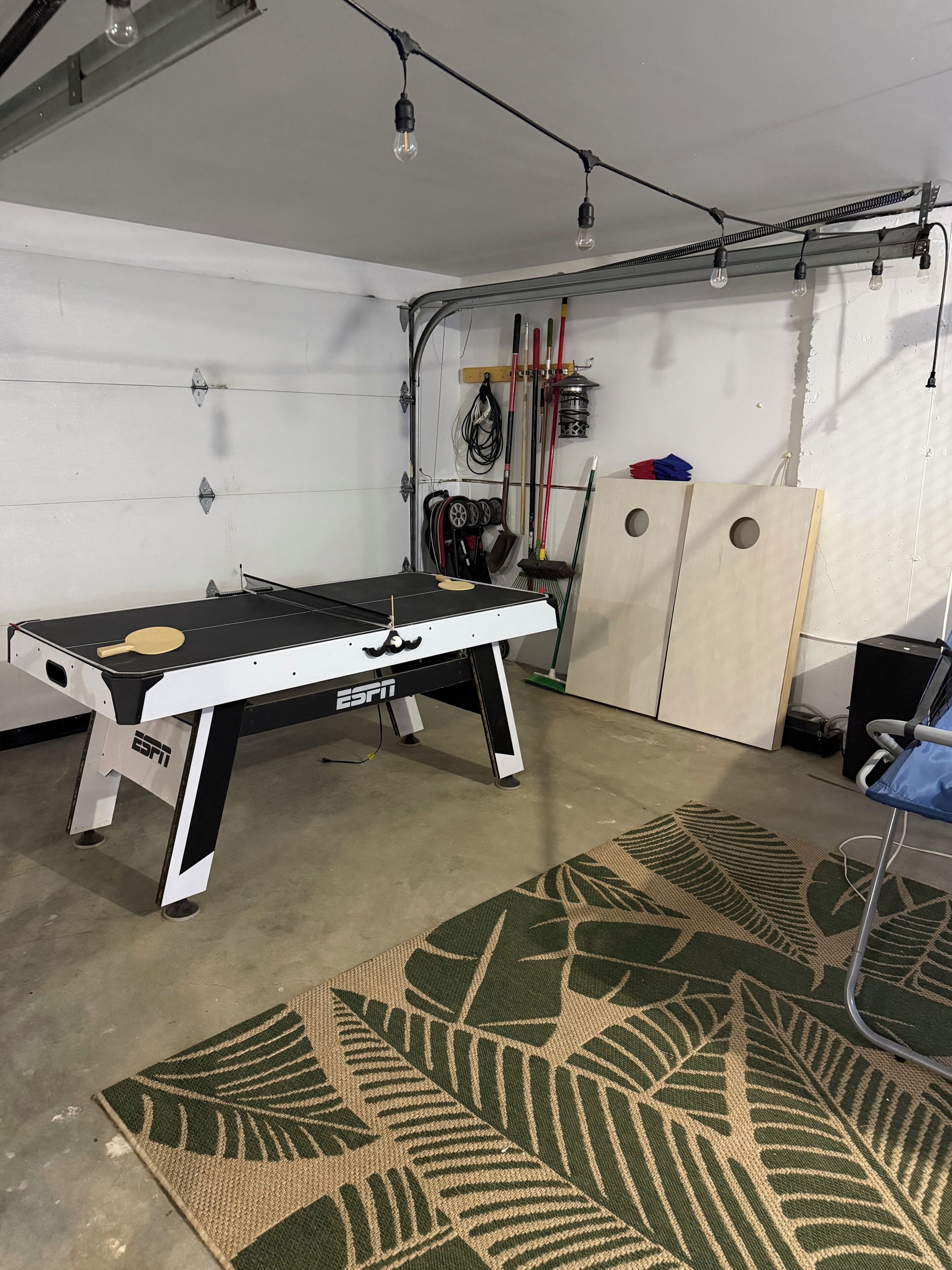 A billiards table with a logo, a patterned rug, and a wall-mounted rack with various items.