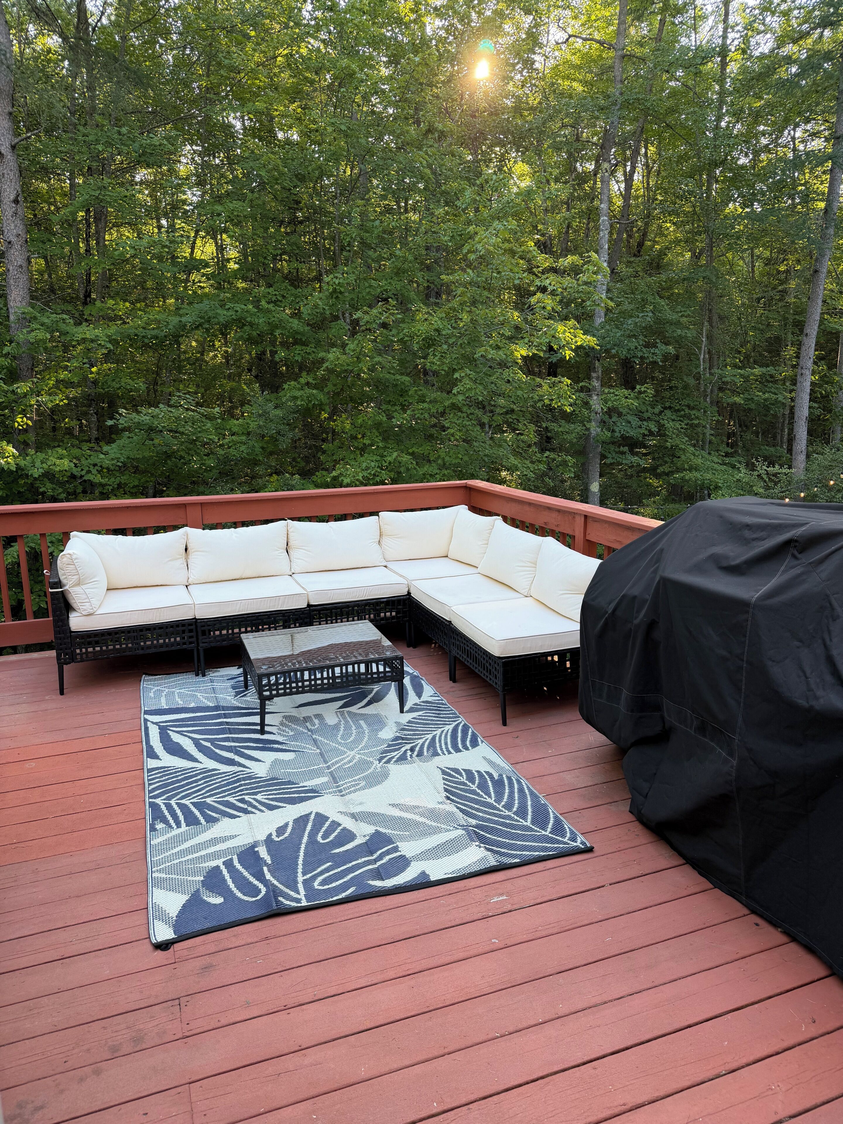 Une terrasse extérieure avec un canapé modulable, une table basse et un barbecue.